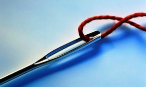 Needle, red thread through eye, close-up (Digital Enhancement)